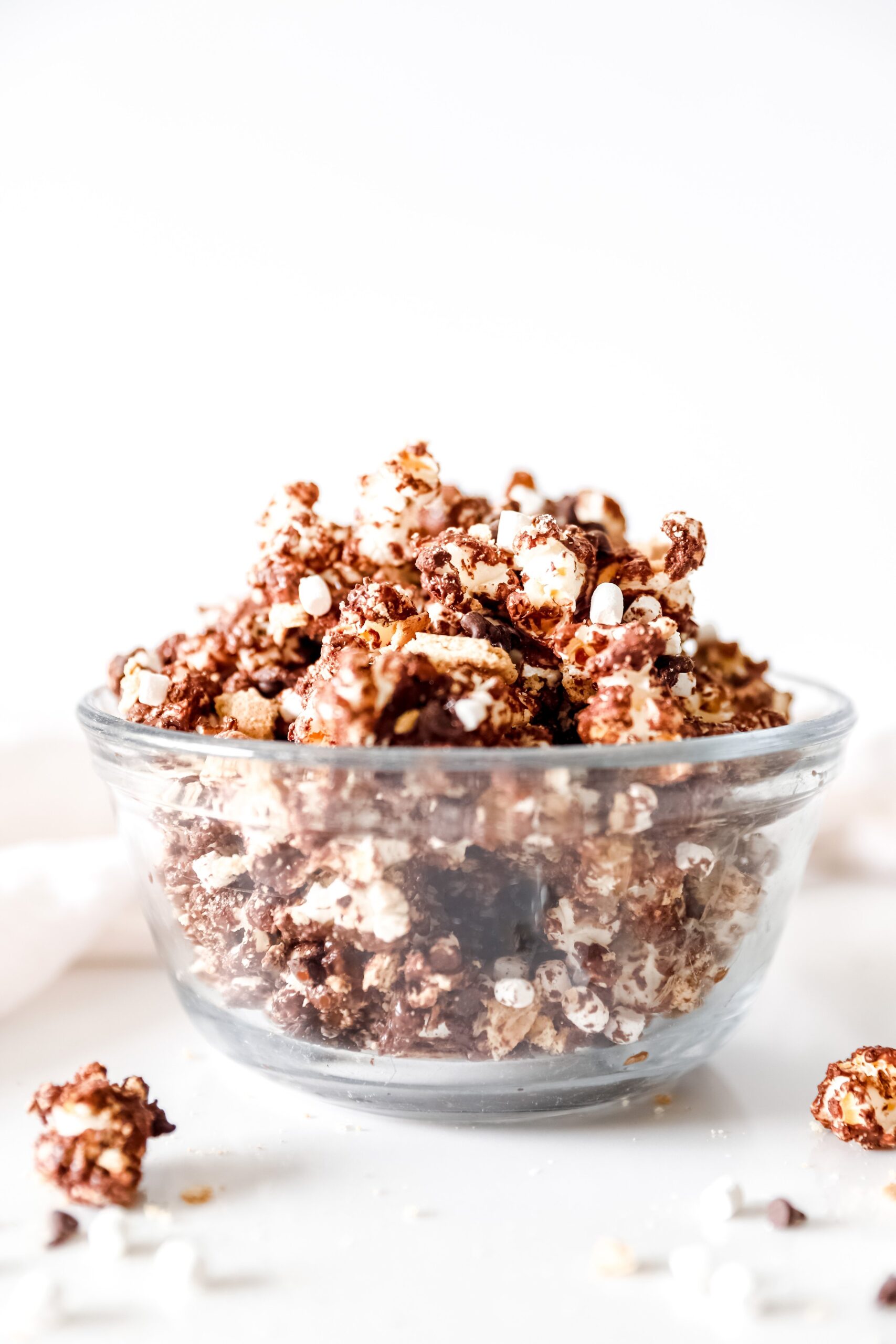 A large bowl of s’mores popcorn loaded with melted chocolate, graham cracker pieces, and mini marshmallows.