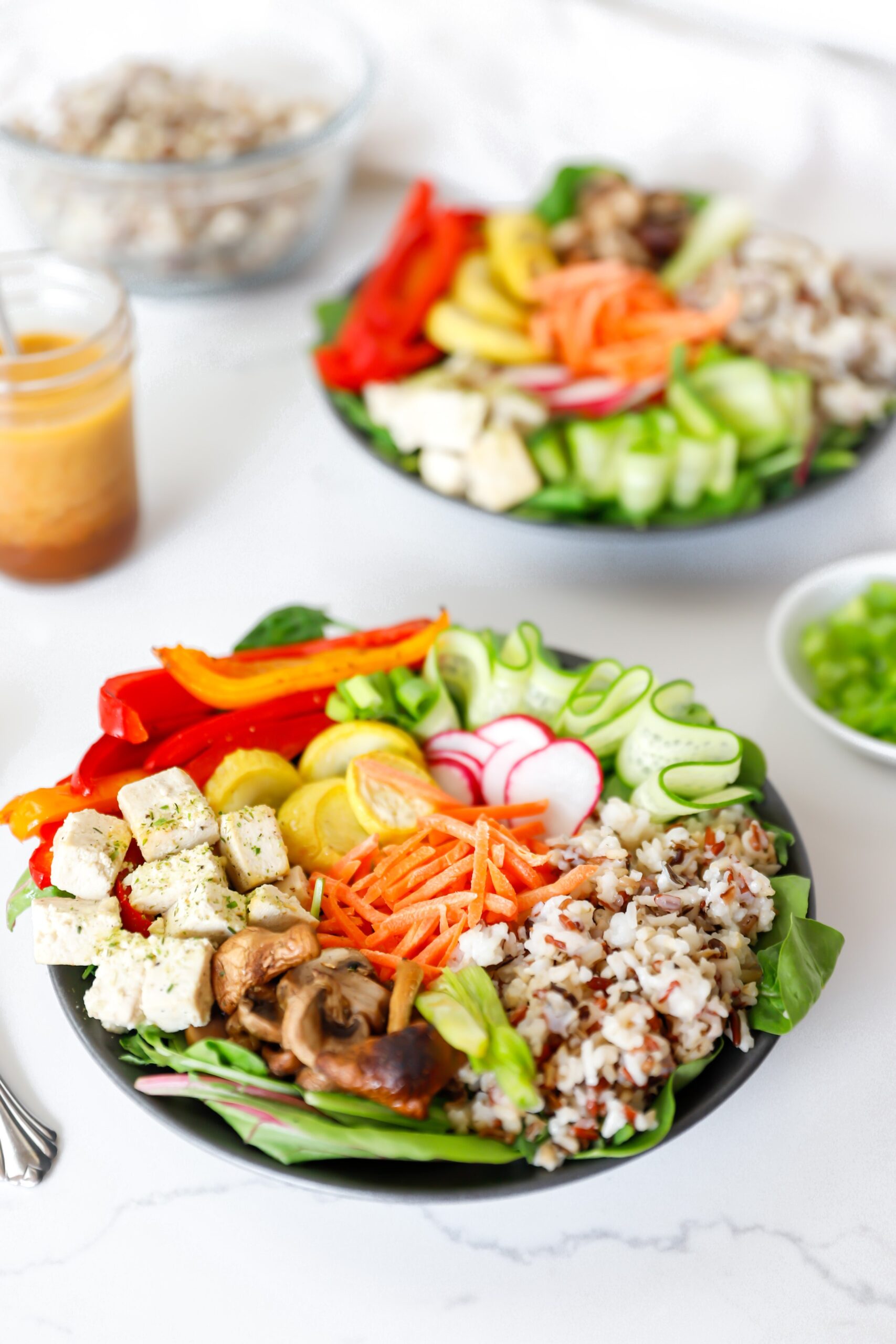 Close-up of a fully assembled Buddha Bowl with tofu, greens, and a drizzle of ginger dressing