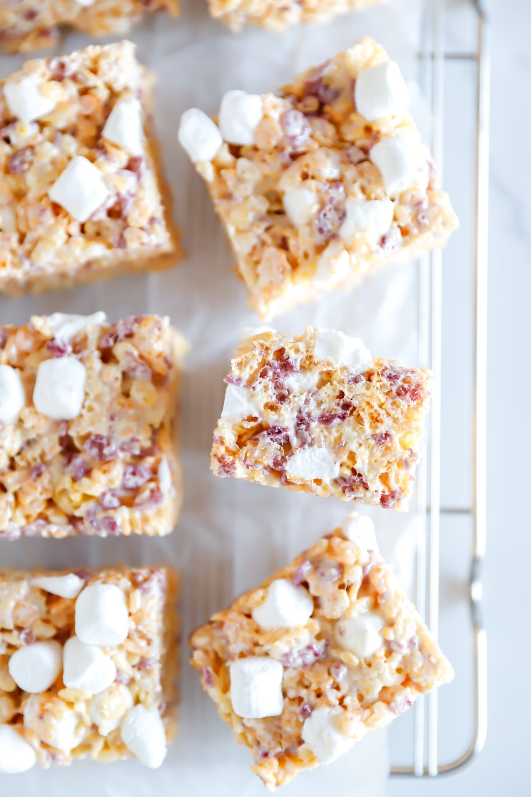 Colorful fruity rice krispy treats made with fruity crispy rice cereal, mini marshmallows, and sweetened condensed milk, topped with extra marshmallows for a gooey, crunchy bite.