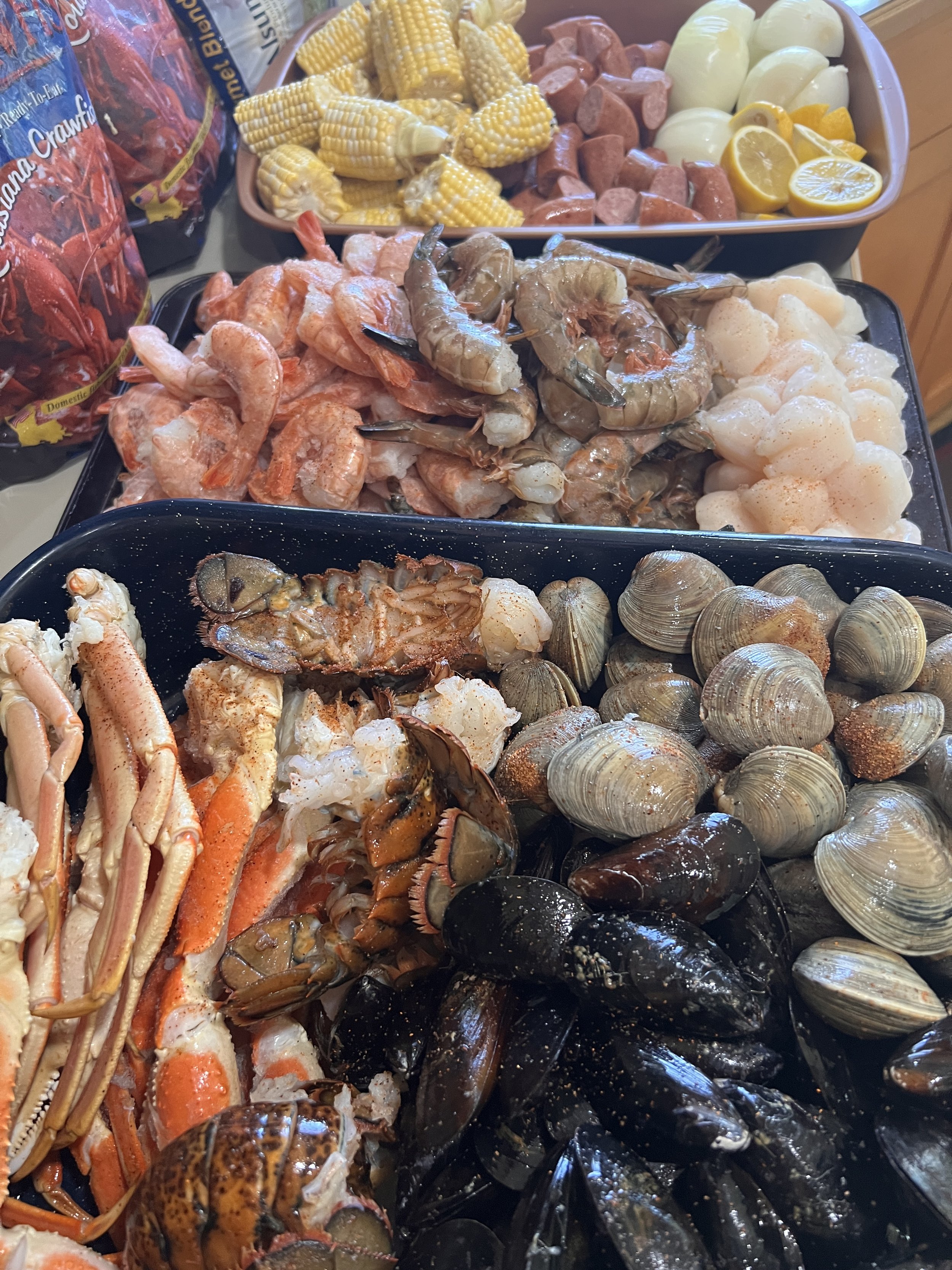 Overhead shot of fresh seafood, corn, potatoes, and sausage on a tray.