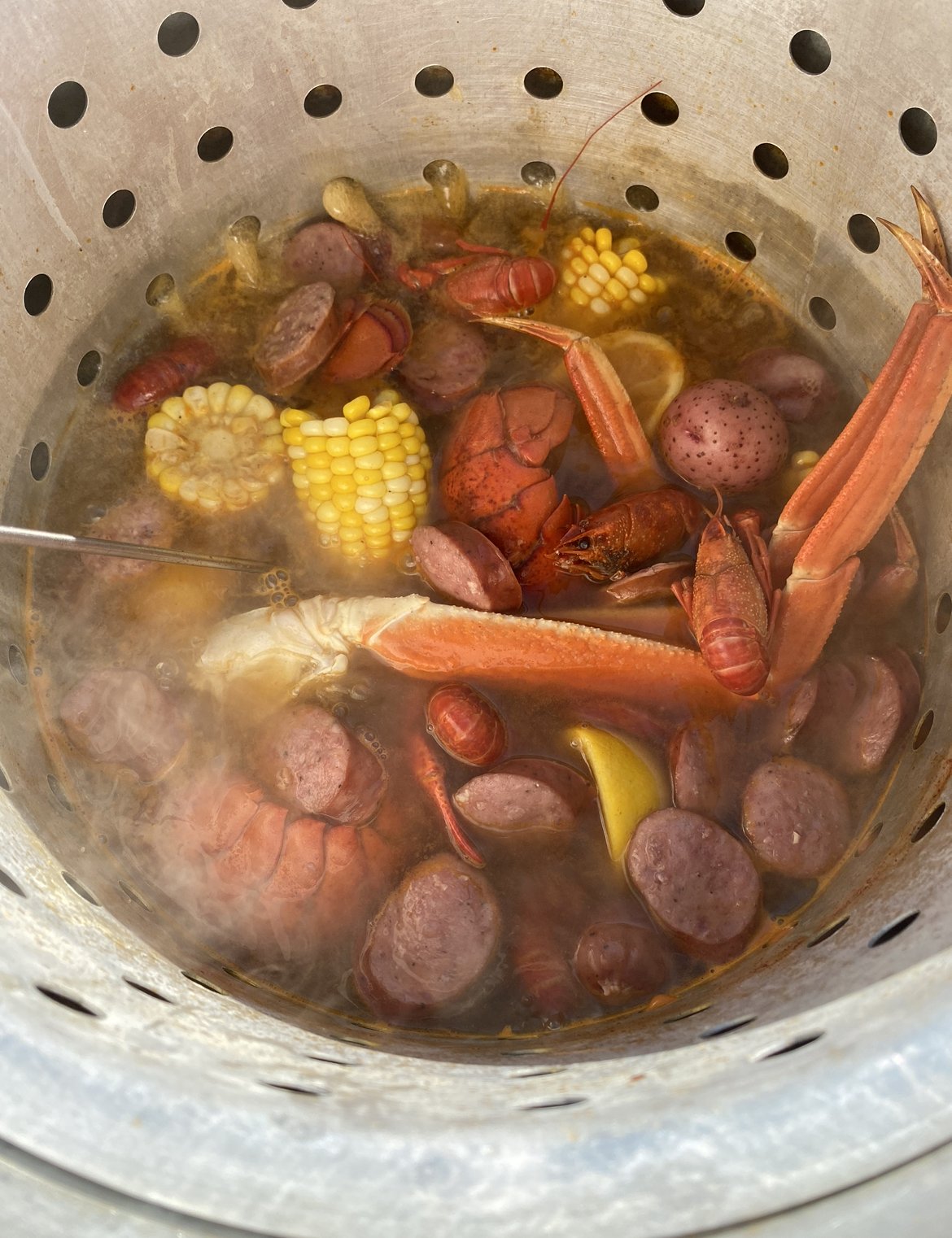 Large stockpot on a propane burner with seafood cooking inside.