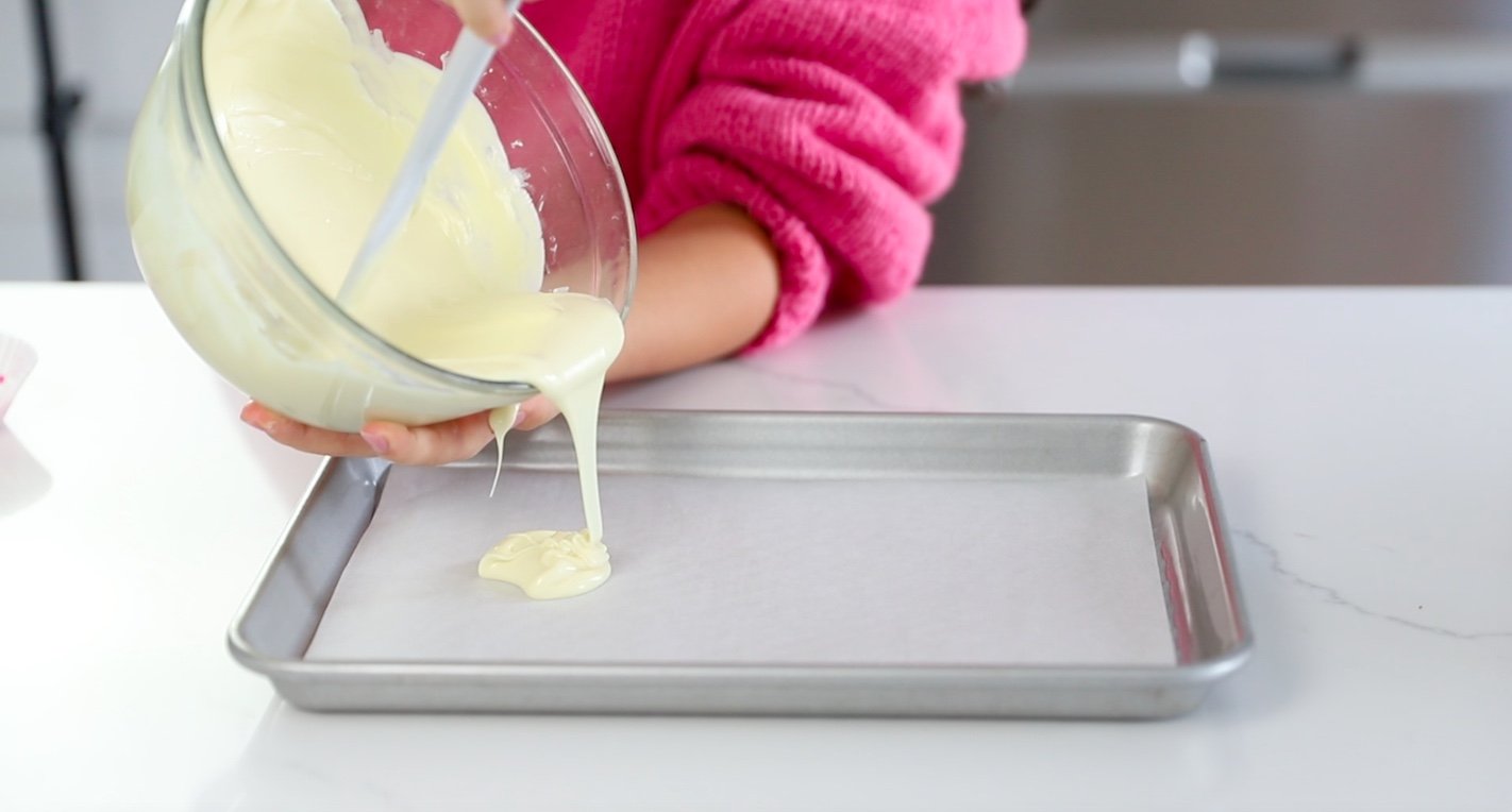 STEP FIVE: Pour melted white chocolate onto a parchment lined baking sheet