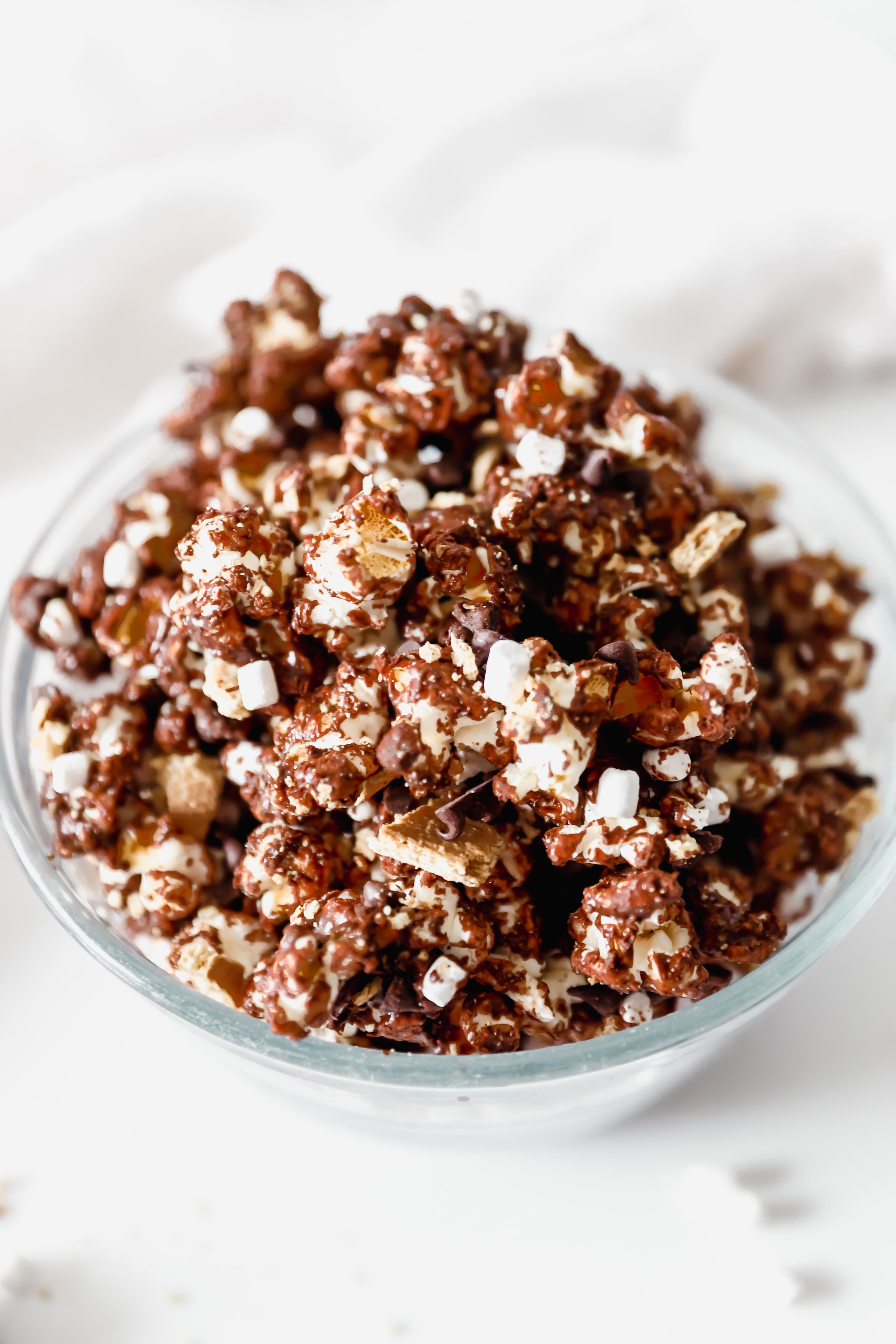 A large bowl of s’mores popcorn loaded with melted chocolate, graham cracker pieces, and mini marshmallows.