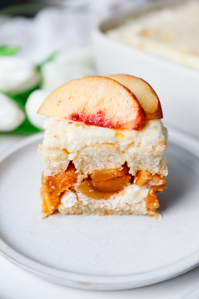 Close up slice of peach tiramisu showing layers of peaches, cream, and ladyfingers