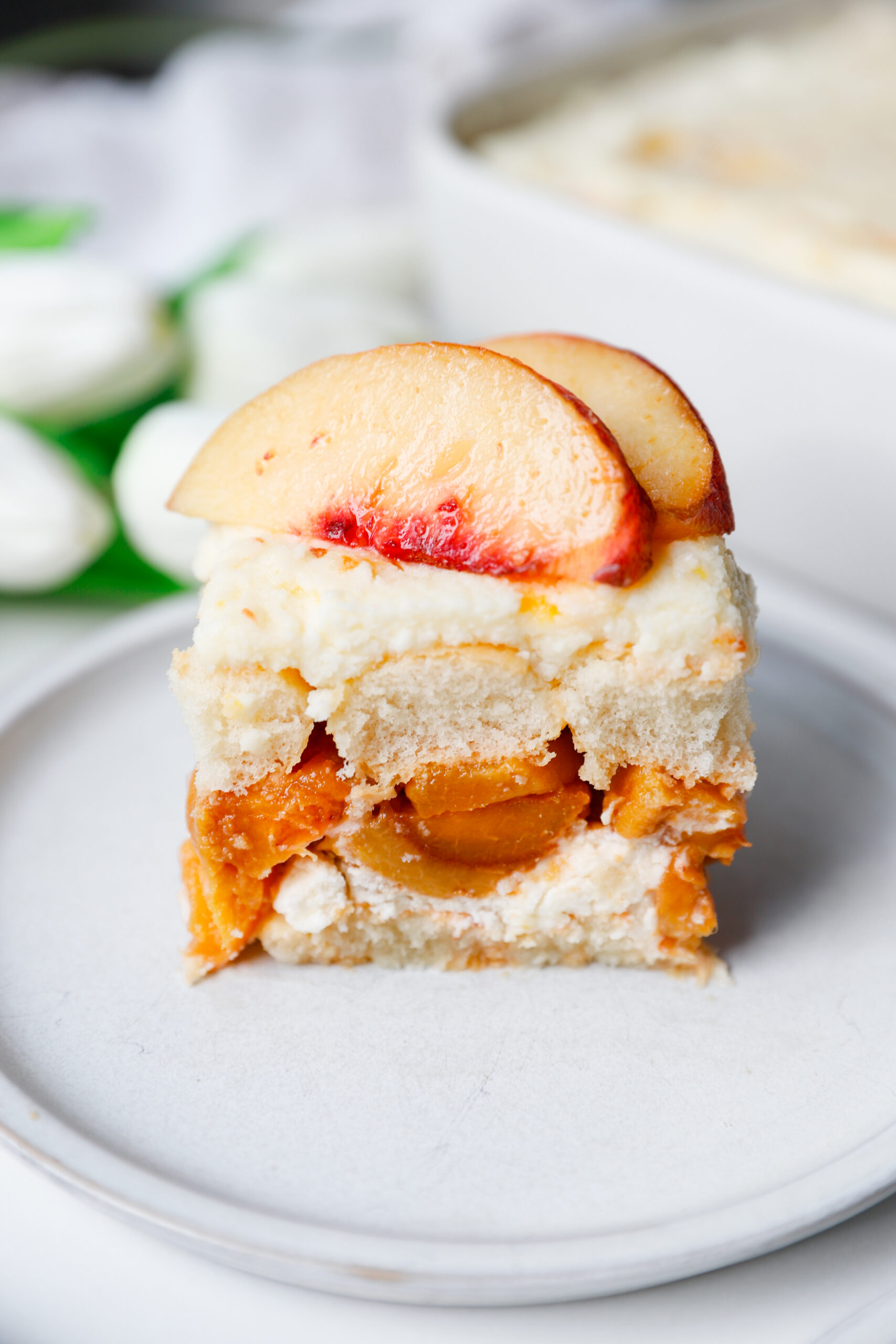 Close up slice of peach tiramisu showing layers of peaches, cream, and ladyfingers