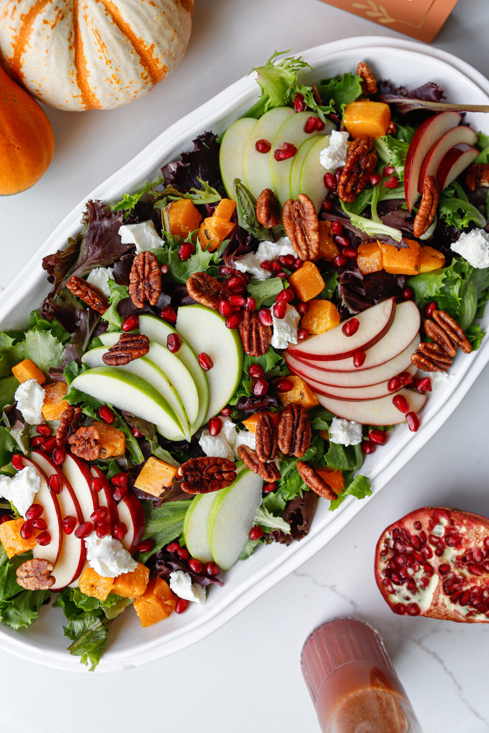 Overhead photo of Autumn Harvest Salad with apples, pecans, squash, and goat cheese in a white serving platter
