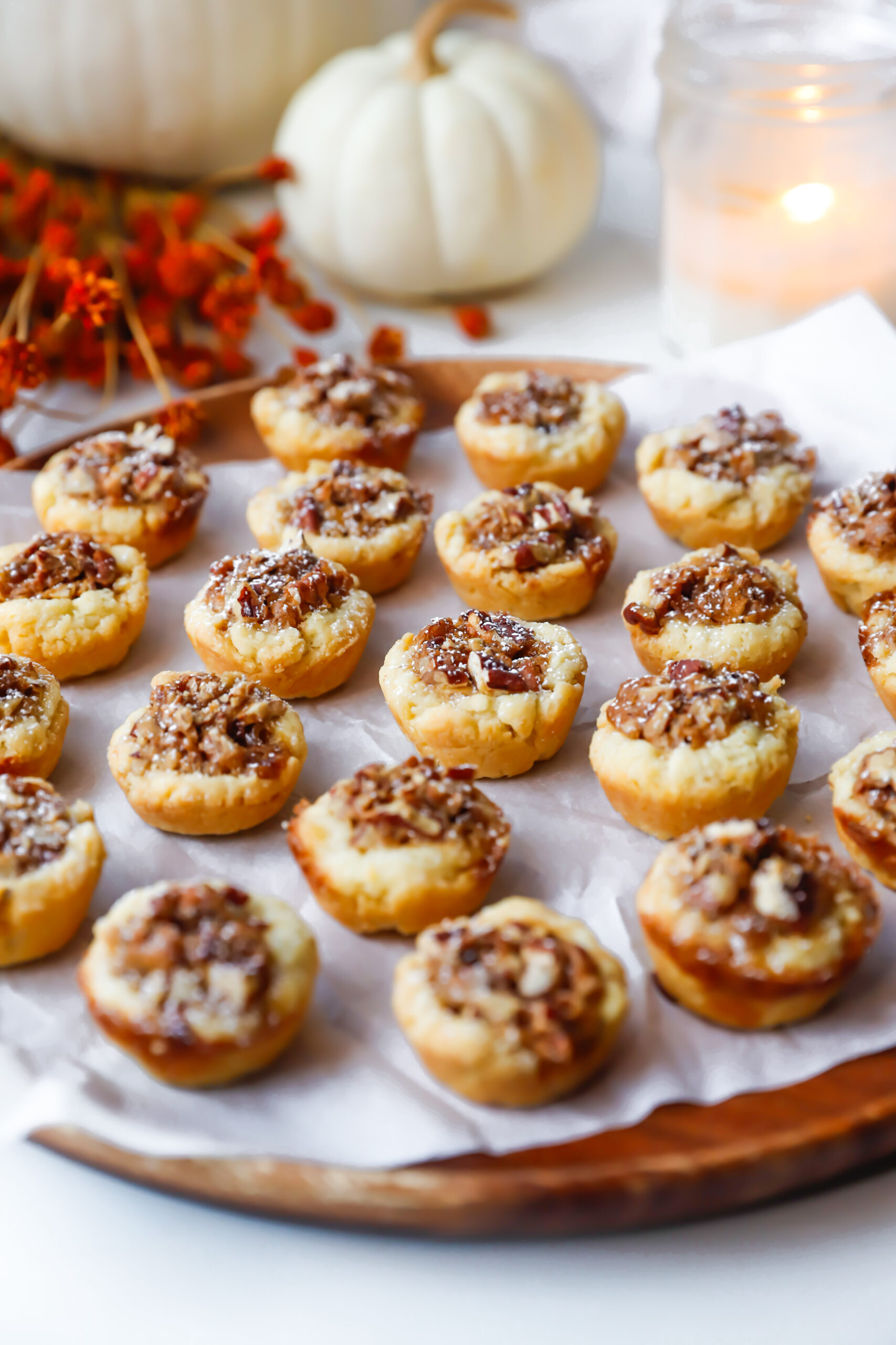 Mini pecan tassies arranged on a wooden parchment lined platter