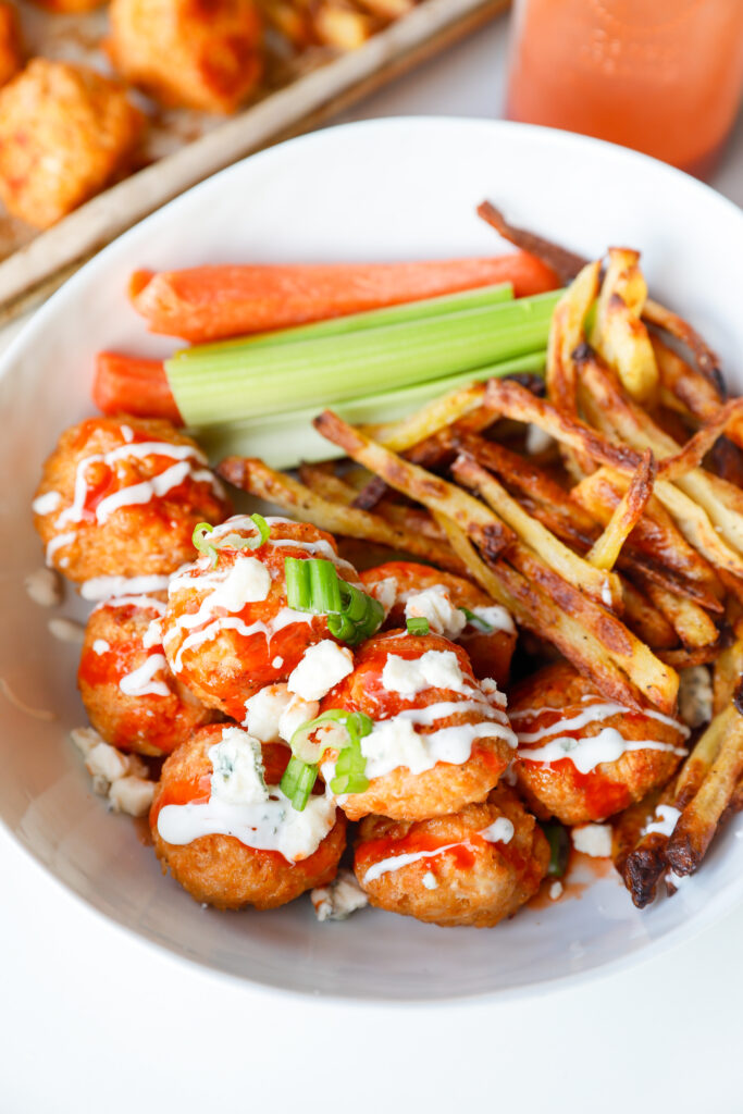 Buffalo chicken meatballs and french fries plated with drizzled buffalo sauce and ranch