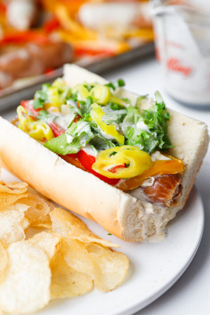 Close-up of sheet pan sausage and pepper grinder subs stuffed into hoagie rolls.