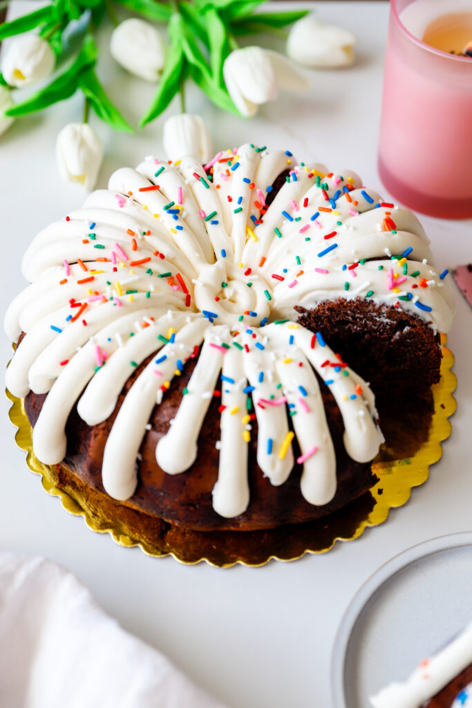 Moist chocolate chocolate chip bundt cake with cream cheese frosting and one slice removed